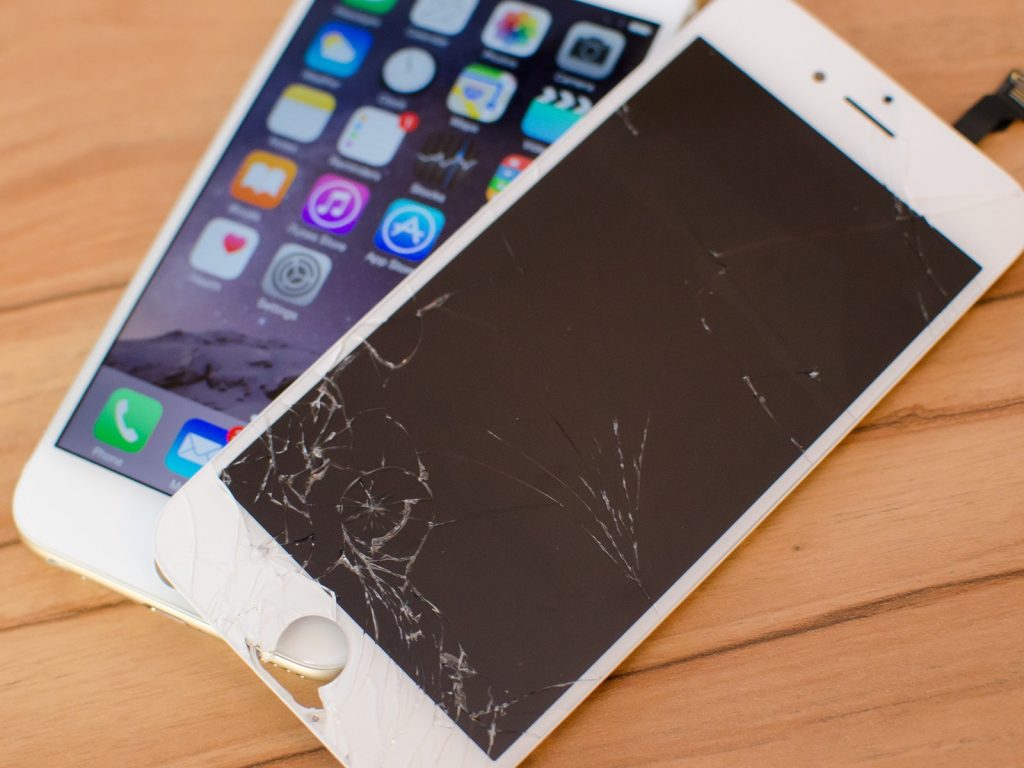 iPhone 6 with a broken screen, laying on top of a new iPhone 6
