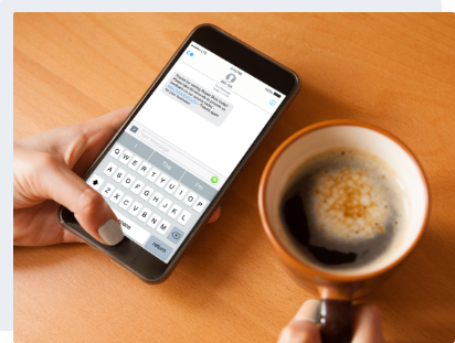 Capture Feedback female hands holding a cup with coffee and an iPhone displaying a text message from a company attempting post sales engagement