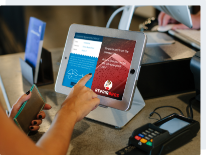 A woman signing a signature page on a customer-facing ipad at a POS