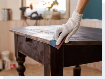 A hand in a glove repolishing a wooden table