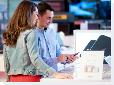 Shopping for a new smart phone A man standing holding a phone in his hand and showing a woman, standing next to him, what is on his screen.