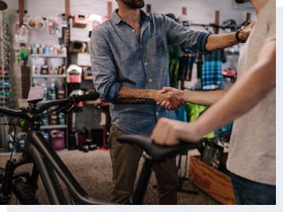 Bicycle shop owner shaking customer hand A bicycle shop owner shaking hands with a male customer who just purchased a bike