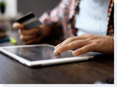 A man sitting at a table making a transaction through an iPad