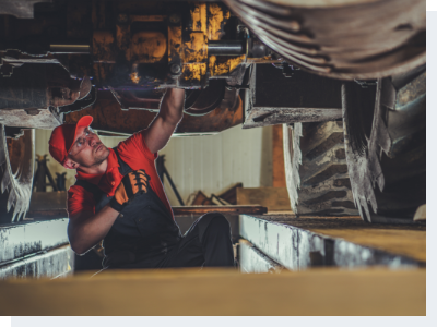 A mechanic working underneath a heavy-duty vehicle